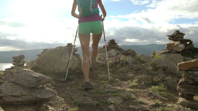 Mujer joven con la mochila que camina alrededor de las montañas y del lago