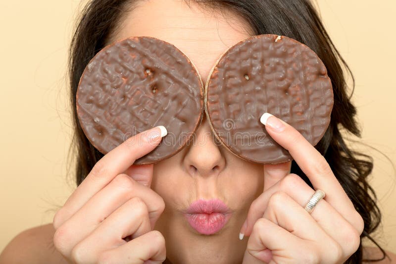 A DSLR royalty free image, of quirky young woman playing with chocolate rice cakes, holding them over her eyes with pursed lips with expression. A DSLR royalty free image, of quirky young woman playing with chocolate rice cakes, holding them over her eyes with pursed lips with expression.