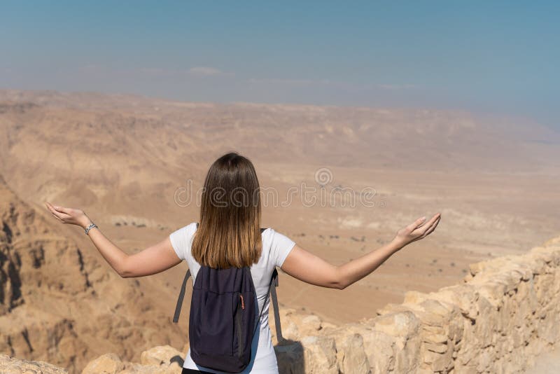 Mujer joven con los brazos aumentados mirando el panorama sobre el desierto en Israel imágenes de archivo libres de regalías Mujer joven con los brazos aumentados mirando el panorama sobre el desierto en Israel imágenes de archivo libres de regalías