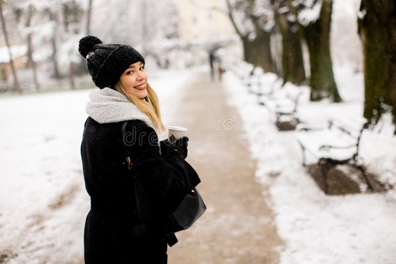 Mujer joven con ropa de abrigo en el frío invierno nieve bebiendo