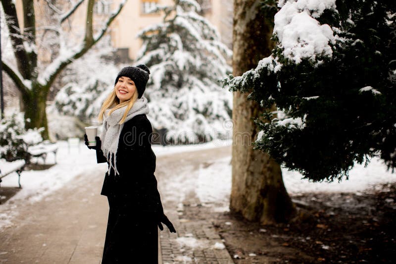 Mujer joven con ropa de abrigo en el frío invierno nieve bebiendo