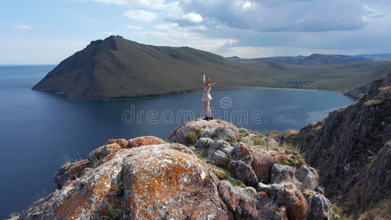 Mujer joven con ropa corta corriendo sobre la montaña por encima del mar