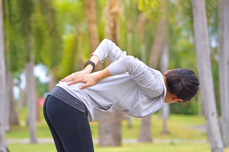 Mujer joven con un dolor más de espalda mientras que corre el ejercicio después de activar en parque imágenes de archivo libres de regalías