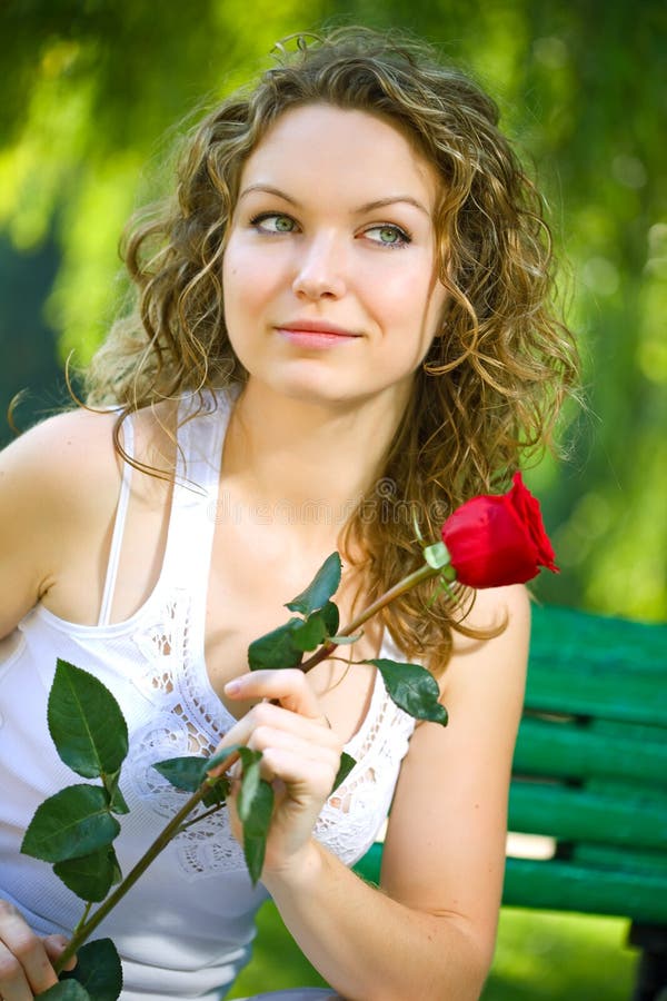 Mujer joven de la belleza en parque con la flor imagen de archivo Mujer joven de la belleza en parque con la flor imagen de archivo