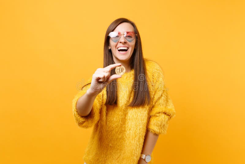 Mujer joven de risa en las lentes del corazón que llevan a cabo el bitcoin, moneda del metal de la moneda de oro del futuro del c fotografía de archivo libre de regalías