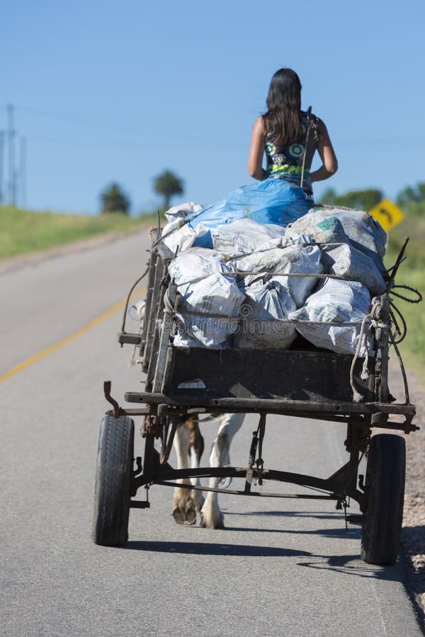 Mujer joven del gaucho y carro traído por caballo en el camino, Uruguay imagen de archivo libre de regalías Mujer joven del gaucho y carro traído por caballo en el camino, Uruguay imagen de archivo libre de regalías