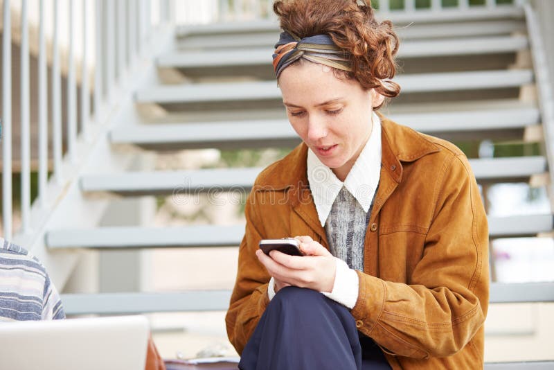 Mujer joven del inconformista del pelirrojo que usa smartphone fotos de archivo Mujer joven del inconformista del pelirrojo que usa smartphone fotos de archivo