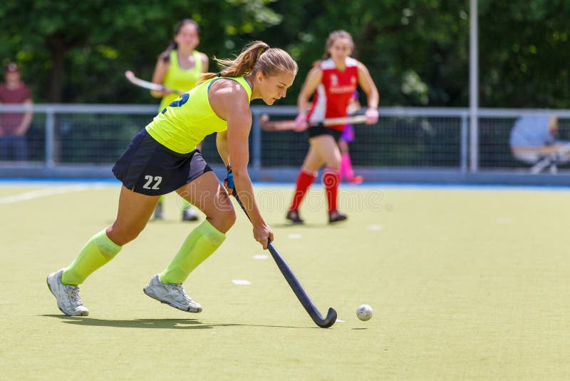Mujer joven del jugador de hockey con la bola en ataque fotos de archivo libres de regalías Mujer joven del jugador de hockey con la bola en ataque fotos de archivo libres de regalías