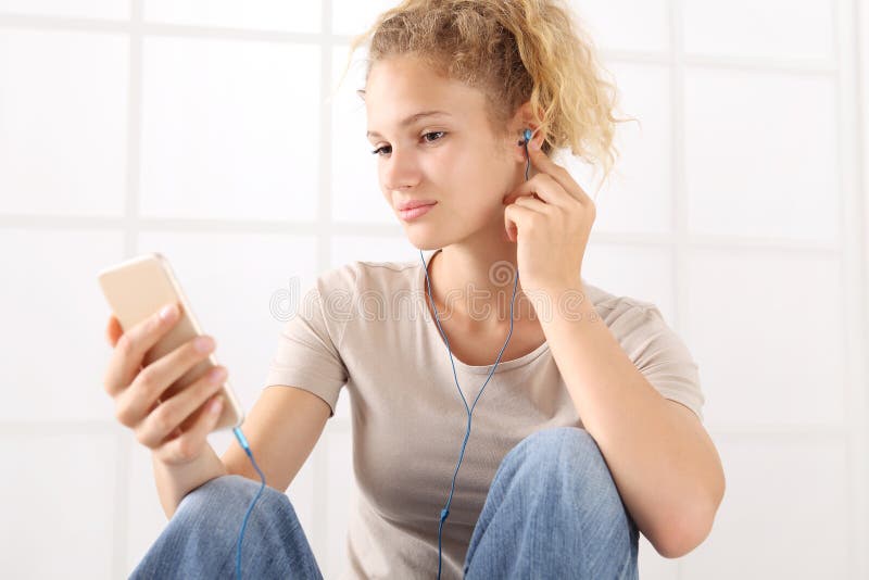 Mujer joven del retrato con smartphone y auriculares, mirada en imagen de archivo libre de regalías Mujer joven del retrato con smartphone y auriculares, mirada en imagen de archivo libre de regalías