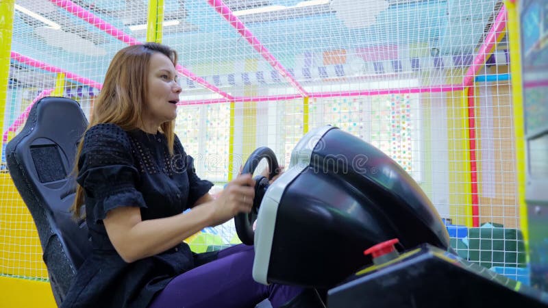 Mujer joven divirtiéndose mientras monta en un simulador de coche
