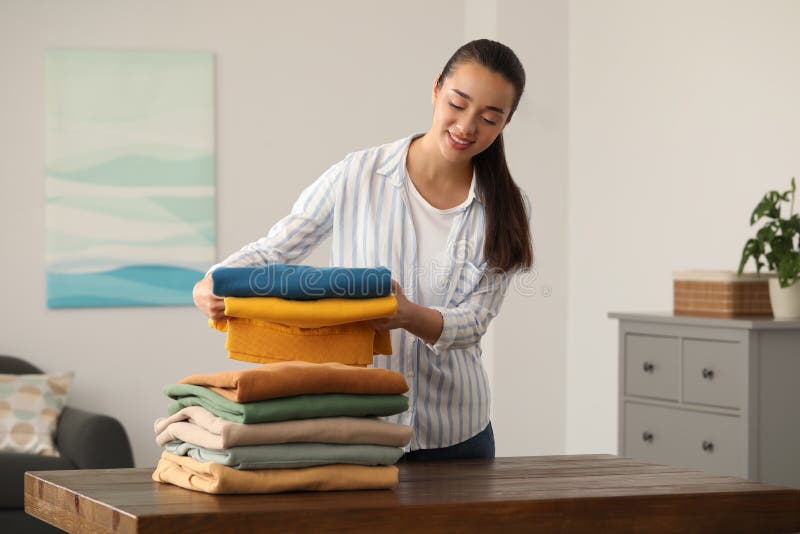 Mujer Joven Doblando Ropa En Una Mesa De Madera En El Interior Imagen de  archivo - Imagen de casero, limpieza: 250466469