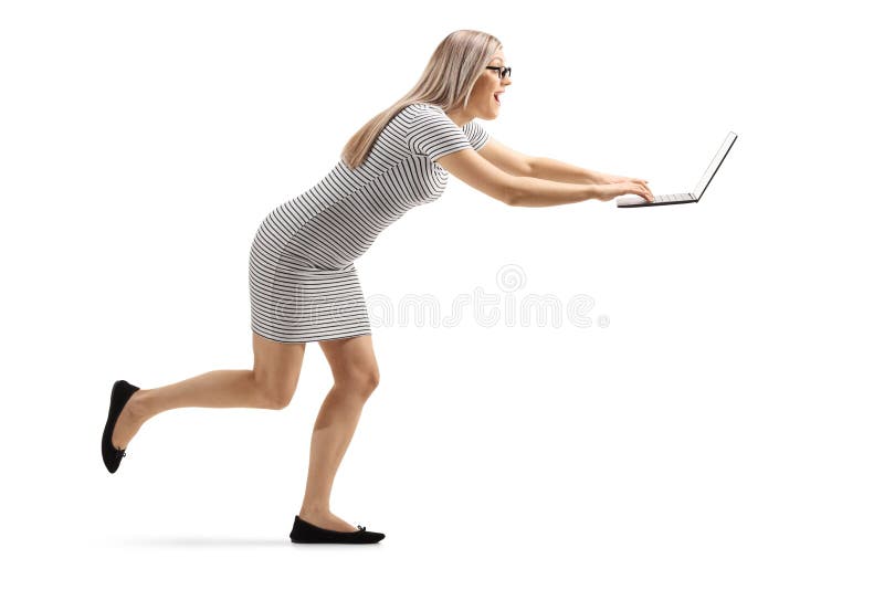 Mujer joven emocionada que corre y que mecanografía en un ordenador portátil foto de archivo