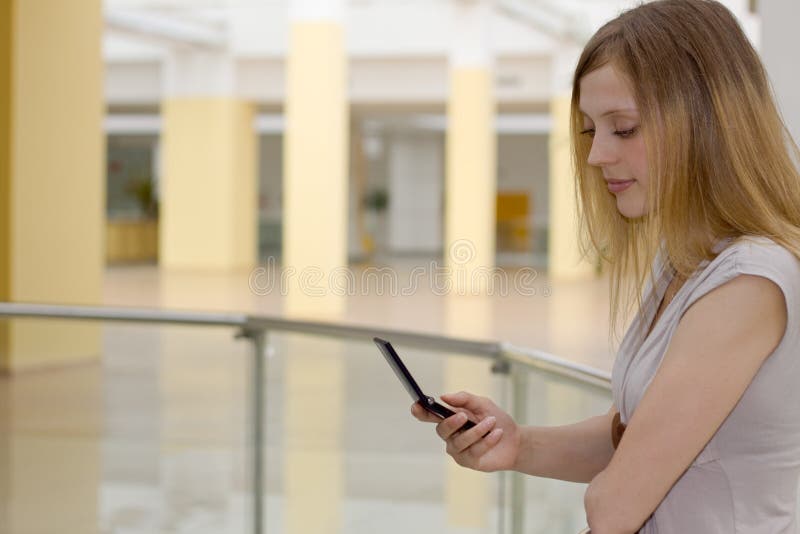 Mujer joven en centro comercial con el teléfono celular fotografía de archivo libre de regalías Mujer joven en centro comercial con el teléfono celular fotografía de archivo libre de regalías