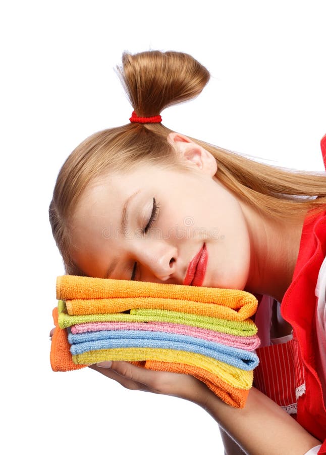 Mujer joven en delantal rojo que duerme en la pila de toallas de té coloridas fotografía de archivo libre de regalías Mujer joven en delantal rojo que duerme en la pila de toallas de té coloridas fotografía de archivo libre de regalías