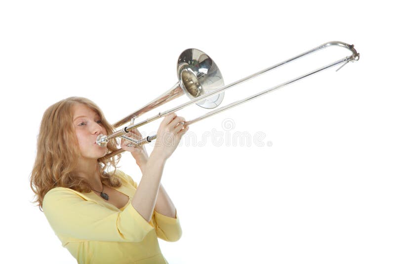 Mujer joven en el mini vestido amarillo que juega el trombón fotografía de archivo Mujer joven en el mini vestido amarillo que juega el trombón fotografía de archivo