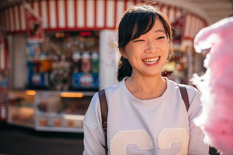 Mujer joven en el parque de atracciones con seda del caramelo imágenes de archivo libres de regalías Mujer joven en el parque de atracciones con seda del caramelo imágenes de archivo libres de regalías