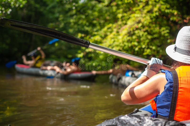 Mujer joven en kajak con el remo en el río salvaje Amigos del grupo en canoa