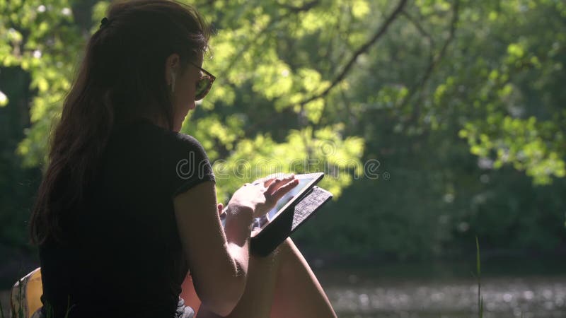 Mujer joven en parque usando la tableta digital