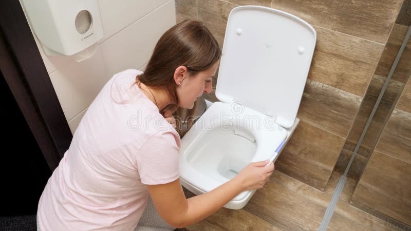 Mujer joven en pijama que se siente enferma con vómitos en el baño después de hacer el test de embarazo. intoxicación y náuseas du metrajes