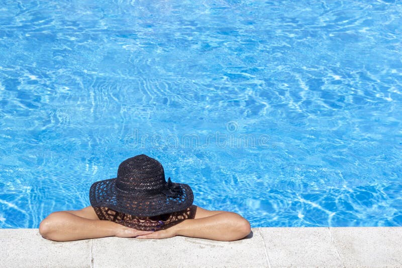 Mujer joven en sombrero negro que disfruta de bronceado en piscina Ocio del día de fiesta en día soleado feliz Concepto de las va foto de archivo libre de regalías Mujer joven en sombrero negro que disfruta de bronceado en piscina Ocio del día de fiesta en día soleado feliz Concepto de las va foto de archivo libre de regalías
