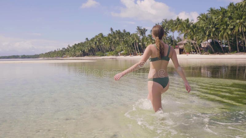 Mujer Joven En Traje De Baño Que Camina En La Agua De Mar Transparente En La Playa Tropical Mujer Que Goza Del Agua Clara E Almacen De Video - Vídeo de asoleado, playa: 138661939