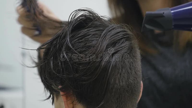 Mujer joven en un salón de pelo que consigue le el pelo hecho el brushing