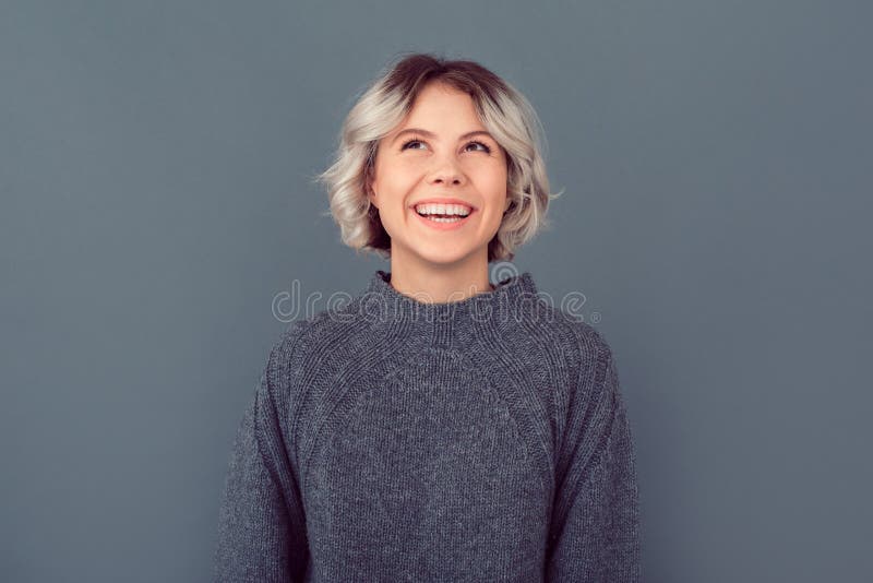 Mujer joven en una imagen gris del estudio del suéter aislada en el fondo gris que mira para arriba fotografía de archivo libre de regalías Mujer joven en una imagen gris del estudio del suéter aislada en el fondo gris que mira para arriba fotografía de archivo libre de regalías