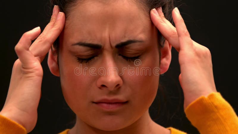 Mujer joven enferma que frota su cabeza en fondo negro metrajes