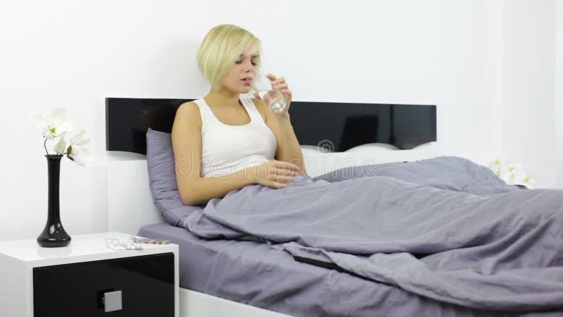 Mujer joven enferma que toma el dormitorio de la medicina en casa almacen de video