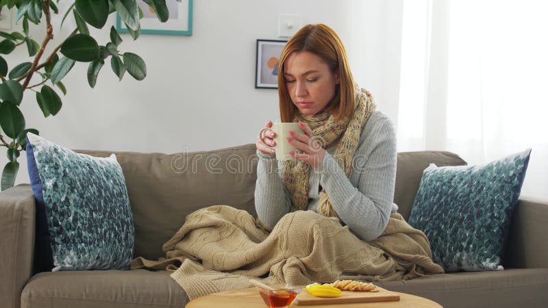Mujer joven enferma tomando té con limón en casa metrajes