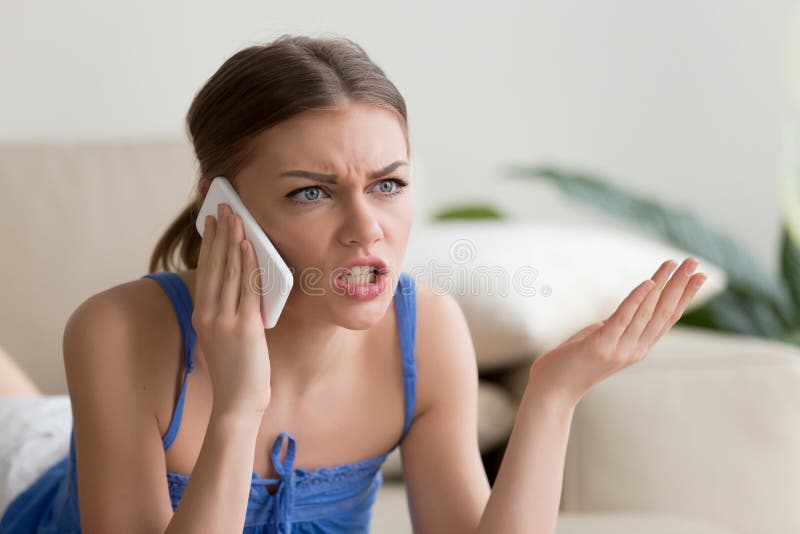 Angry young woman arguing talking on phone at home, dissatisfied girl calling customer service, having problem of conflict during telephone conversation, shouting gesturing while speaking by cell. Angry young woman arguing talking on phone at home, dissatisfied girl calling customer service, having problem of conflict during telephone conversation, shouting gesturing while speaking by cell