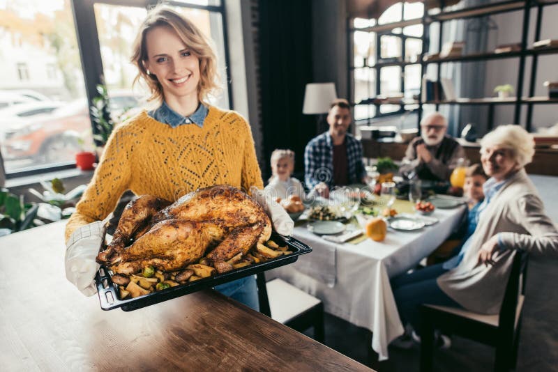 mujer joven feliz con el pavo de la acción de gracias para la cena del día de fiesta con la familia y la mirada fotos de archivo libres de regalías mujer joven feliz con el pavo de la acción de gracias para la cena del día de fiesta con la familia y la mirada fotos de archivo libres de regalías