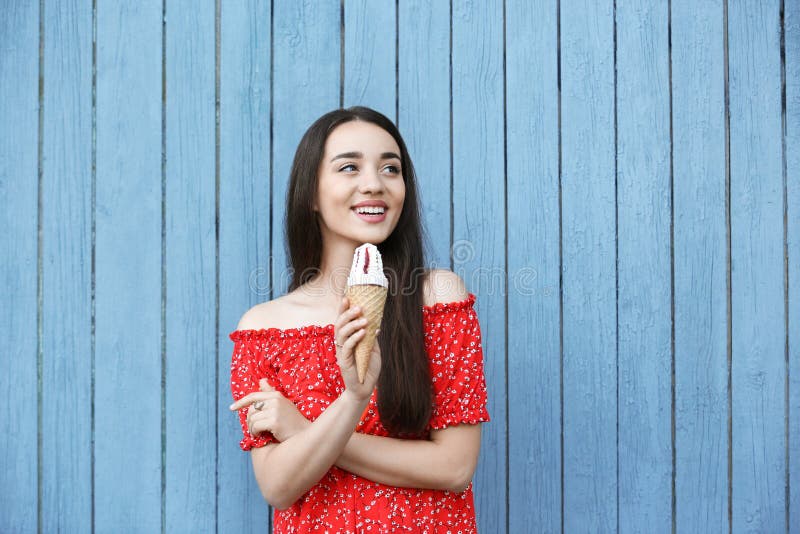Mujer joven feliz con helado delicioso en cono de la galleta cerca de la pared de madera fotos de archivo Mujer joven feliz con helado delicioso en cono de la galleta cerca de la pared de madera fotos de archivo
