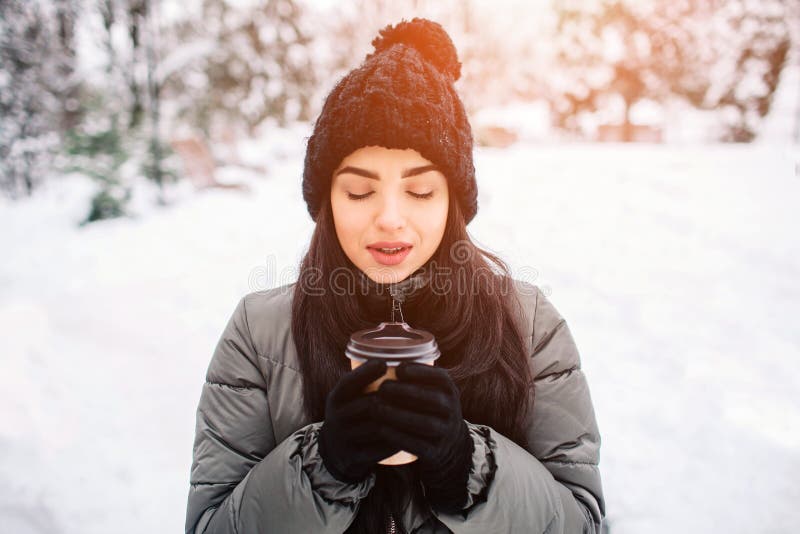 Mujer joven feliz con una taza de té o de café caliente en paseo nevoso del invierno en naturaleza Concepto de estación del invie foto de archivo libre de regalías Mujer joven feliz con una taza de té o de café caliente en paseo nevoso del invierno en naturaleza Concepto de estación del invie foto de archivo libre de regalías