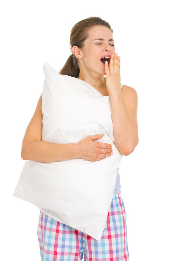 Happy young woman in pajamas with pillow yawing isolated on white. Happy young woman in pajamas with pillow yawing isolated on white