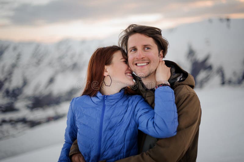 Mujer joven feliz que besa a su novio sonriente en montañas fotos de archivo libres de regalías Mujer joven feliz que besa a su novio sonriente en montañas fotos de archivo libres de regalías
