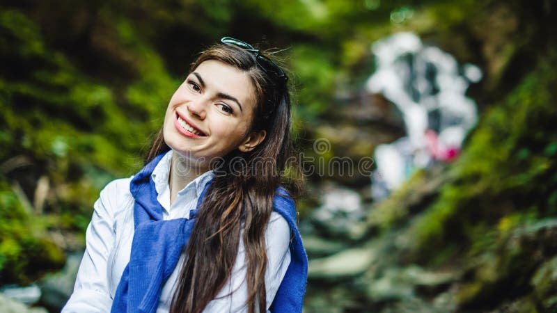 Mujer joven feliz que disfruta de la naturaleza con la cascada en fondo foto de archivo libre de regalías Mujer joven feliz que disfruta de la naturaleza con la cascada en fondo foto de archivo libre de regalías
