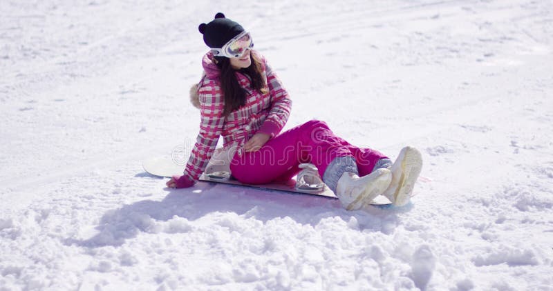 Mujer joven feliz sentada en snowboard almacen de video