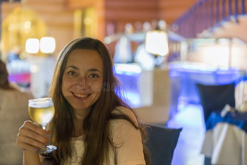 Mujer joven hermosa con una copa de vino en un fondo borroso imágenes de archivo libres de regalías Mujer joven hermosa con una copa de vino en un fondo borroso imágenes de archivo libres de regalías