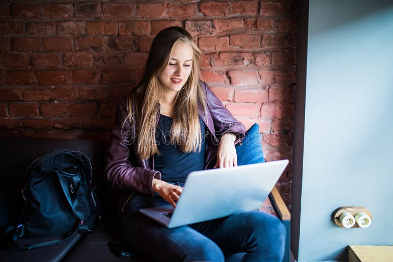 Mujer joven hermosa del freelancer que usa el ordenador portátil que se sienta en la tabla del café Muchacha sonriente feliz que imagen de archivo Mujer joven hermosa del freelancer que usa el ordenador portátil que se sienta en la tabla del café Muchacha sonriente feliz que imagen de archivo