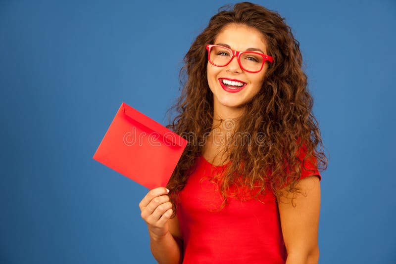 Mujer joven hermosa en el rojo que sostiene el sobre rojo fotos de archivo libres de regalías Mujer joven hermosa en el rojo que sostiene el sobre rojo fotos de archivo libres de regalías