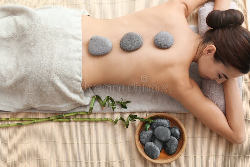 Mujer joven hermosa que consigue masaje de piedra caliente en salón del balneario imagen de archivo libre de regalías Mujer joven hermosa que consigue masaje de piedra caliente en salón del balneario imagen de archivo libre de regalías