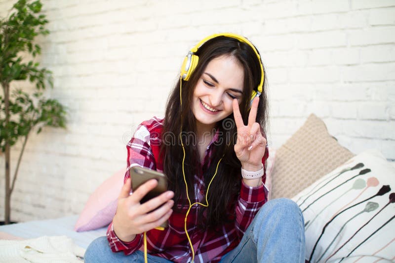 Mujer joven hermosa que escucha la música en auriculares en casa fotografía de archivo Mujer joven hermosa que escucha la música en auriculares en casa fotografía de archivo