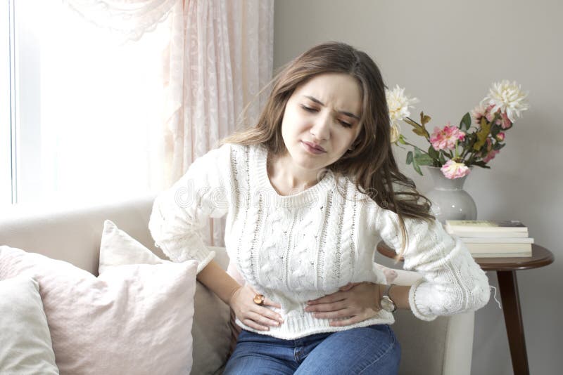 Mujer joven hermosa que sufre de dolor abdominal en casa fotografía de archivo libre de regalías Mujer joven hermosa que sufre de dolor abdominal en casa fotografía de archivo libre de regalías