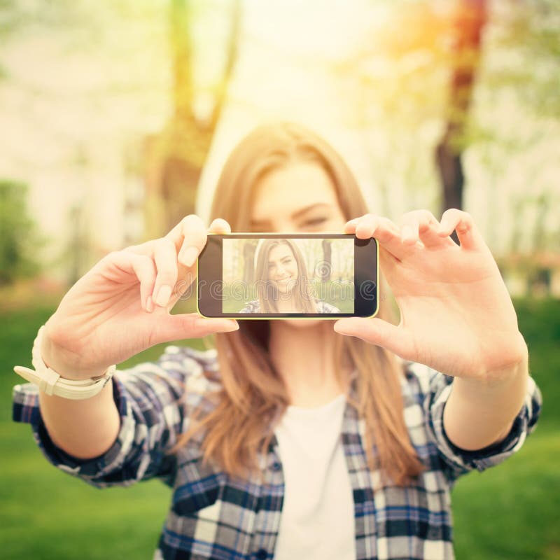 Mujer joven hermosa que toma una foto del selfie con el teléfono imagen de archivo