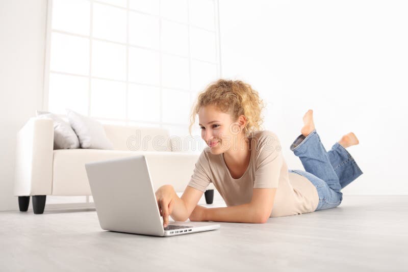 Mujer joven hermosa sonriente que usa un ordenador portátil, mintiendo en el ro de vida imágenes de archivo libres de regalías Mujer joven hermosa sonriente que usa un ordenador portátil, mintiendo en el ro de vida imágenes de archivo libres de regalías