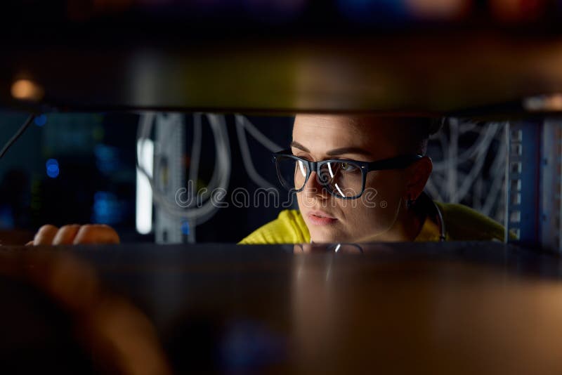 Mujer joven ingeniera informática trabajando en cables de conexión de la sala de datos foto de archivo