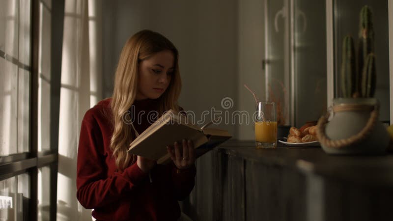 Mujer joven inteligente que lee un libro en casa