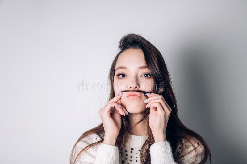Mujer joven preciosa linda que hace el bigote con su pelo foto de archivo Mujer joven preciosa linda que hace el bigote con su pelo foto de archivo