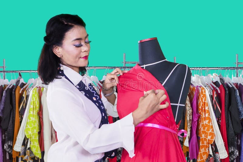 Mujer joven que ajusta un vestido en un maniquí fotografía de archivo libre de regalías Mujer joven que ajusta un vestido en un maniquí fotografía de archivo libre de regalías